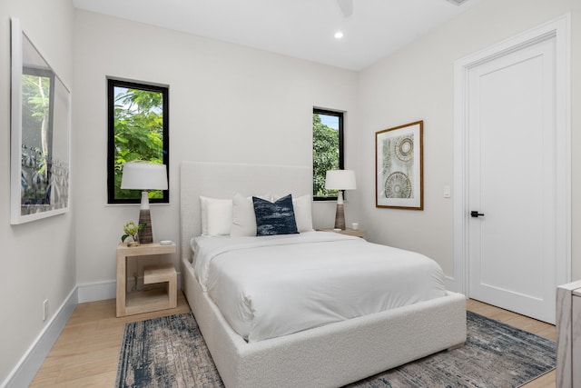 bedroom featuring ceiling fan, multiple windows, and light wood-type flooring