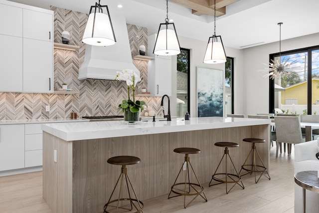 kitchen with a center island with sink, white cabinetry, and a kitchen bar