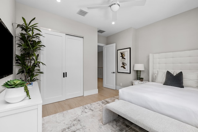 bedroom with a closet, light hardwood / wood-style floors, and ceiling fan