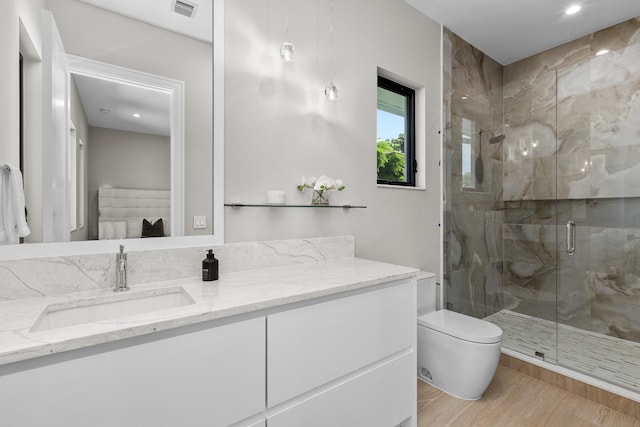 bathroom with toilet, hardwood / wood-style floors, vanity, and a shower with door