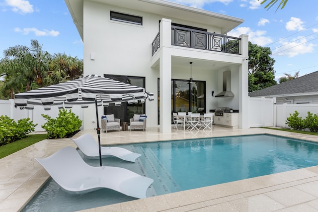 back of house with a patio area, a fenced in pool, a balcony, and an outdoor kitchen