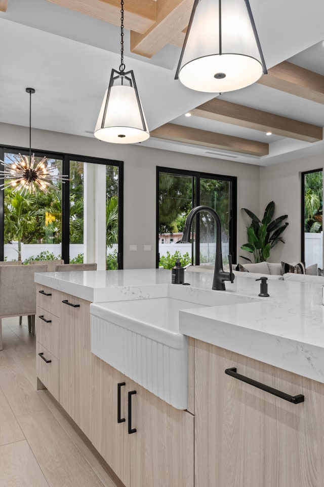 kitchen featuring light hardwood / wood-style floors, light brown cabinets, light stone counters, and hanging light fixtures