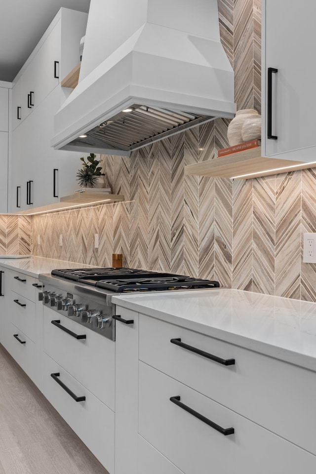 kitchen featuring custom exhaust hood, decorative backsplash, light stone counters, and white cabinets