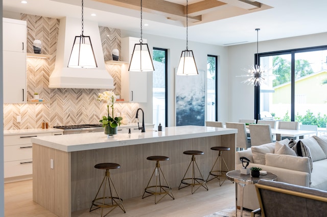 kitchen featuring white cabinetry, light hardwood / wood-style floors, a breakfast bar, and pendant lighting