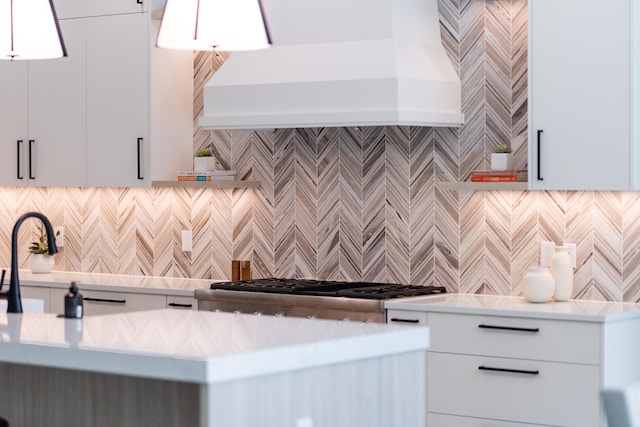 kitchen with stainless steel stove, custom exhaust hood, white cabinetry, and backsplash