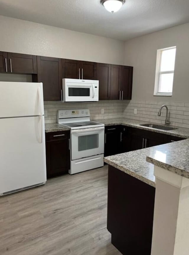 kitchen with sink, white appliances, light hardwood / wood-style flooring, backsplash, and light stone countertops