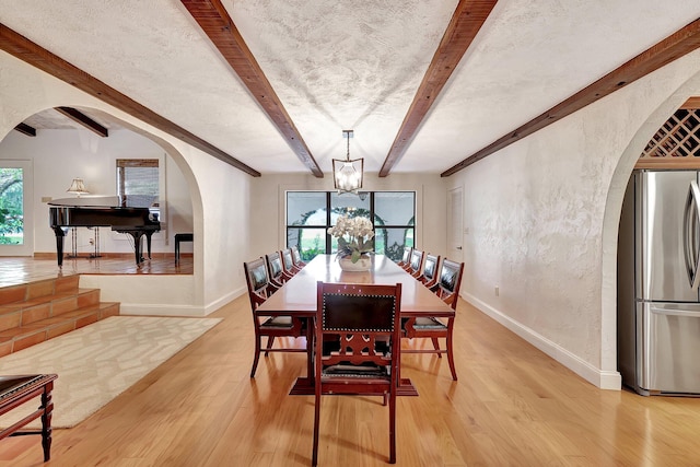 dining area featuring beamed ceiling, a textured ceiling, light hardwood / wood-style flooring, and a notable chandelier