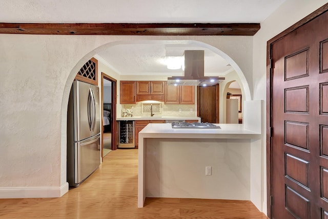 kitchen featuring island exhaust hood, decorative backsplash, stainless steel appliances, light hardwood / wood-style floors, and wine cooler