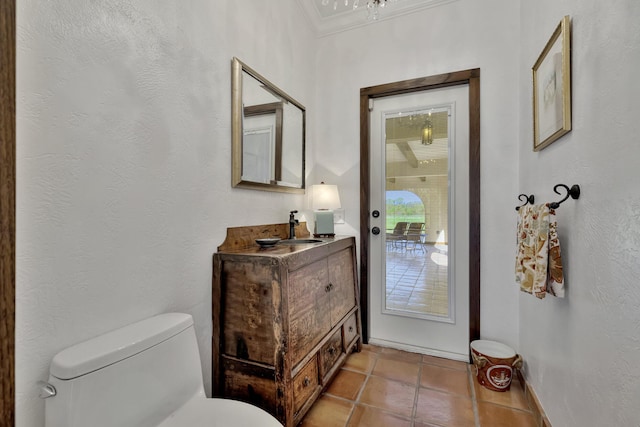 bathroom featuring tile patterned flooring, vanity, ornamental molding, and toilet