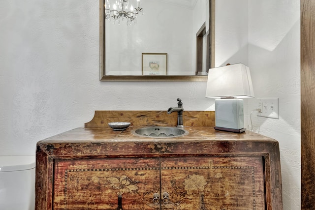 bathroom with vanity, toilet, and an inviting chandelier