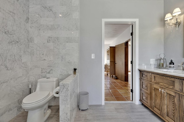 bathroom with tile patterned floors, vanity, toilet, and tile walls