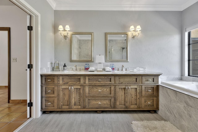 bathroom with hardwood / wood-style floors, vanity, a relaxing tiled tub, and crown molding