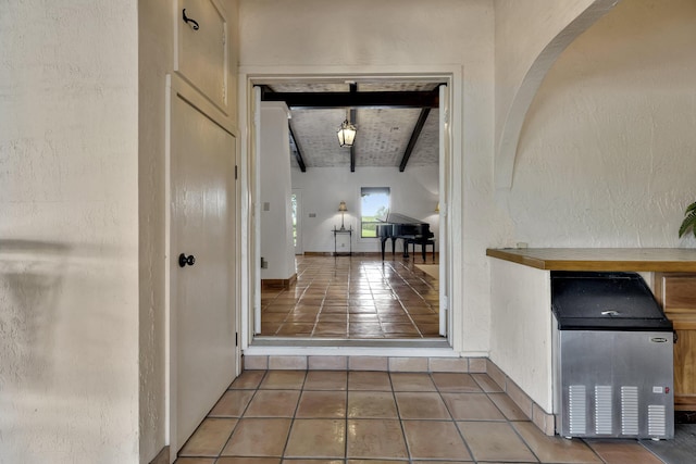 hall featuring tile patterned floors, vaulted ceiling with beams, and wooden ceiling