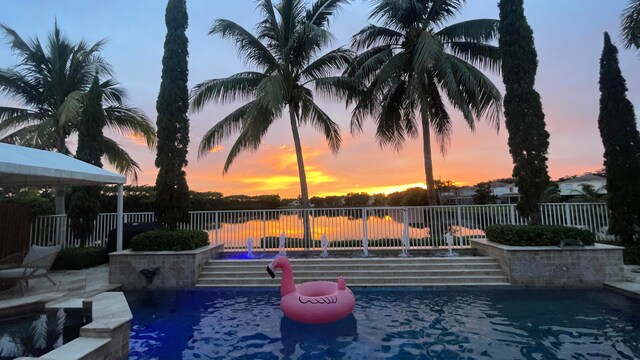 pool at dusk featuring pool water feature