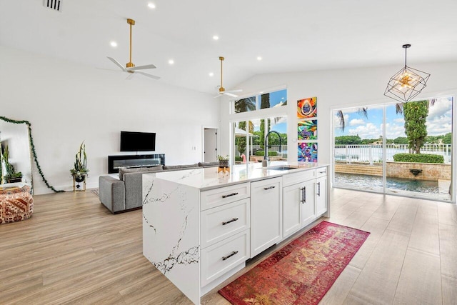 kitchen with white cabinetry, a wealth of natural light, a ceiling fan, and a sink