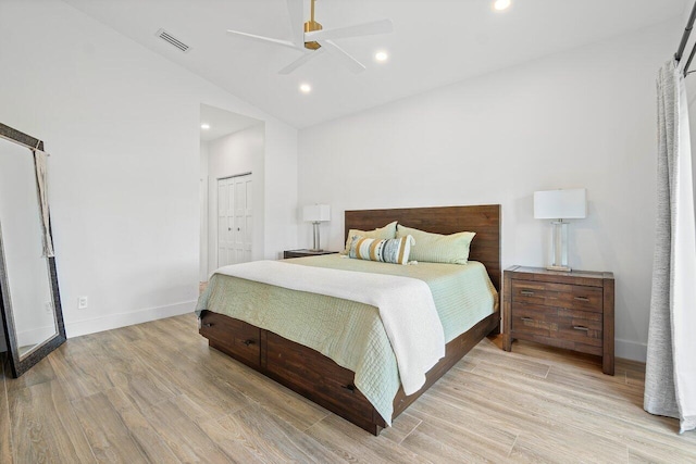 bedroom with a closet, a barn door, lofted ceiling, ceiling fan, and light hardwood / wood-style flooring