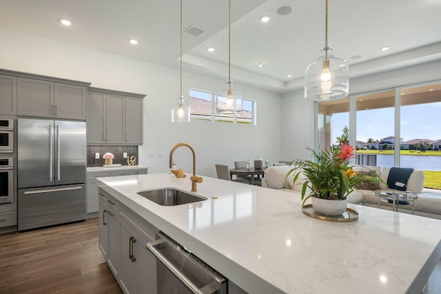 kitchen with appliances with stainless steel finishes, gray cabinetry, sink, a water view, and decorative light fixtures