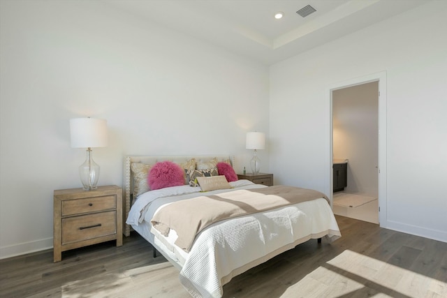 bedroom with connected bathroom and dark hardwood / wood-style flooring