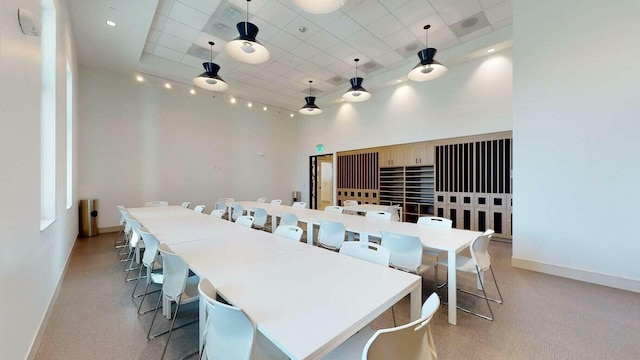 dining area featuring a high ceiling, light colored carpet, and a raised ceiling