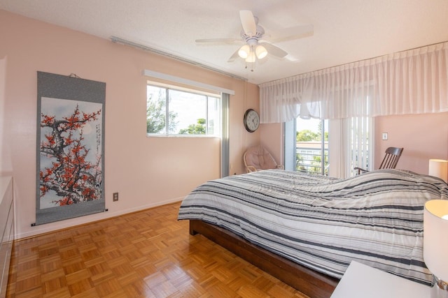 bedroom featuring ceiling fan, light parquet floors, and a textured ceiling