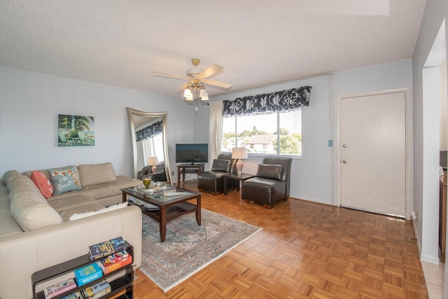 living room featuring parquet flooring, ceiling fan, and a textured ceiling