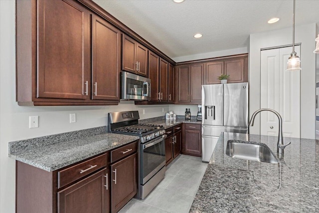 kitchen featuring dark stone countertops, a textured ceiling, appliances with stainless steel finishes, and sink