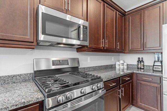 kitchen featuring appliances with stainless steel finishes, a textured ceiling, and dark stone countertops