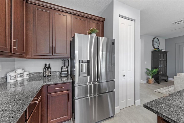 kitchen featuring a textured ceiling, stainless steel refrigerator with ice dispenser, dark stone countertops, and light hardwood / wood-style floors