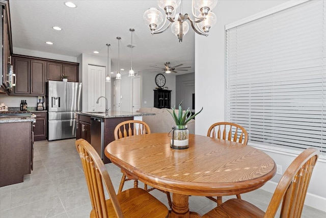 dining room featuring light tile patterned floors, ceiling fan with notable chandelier, and sink