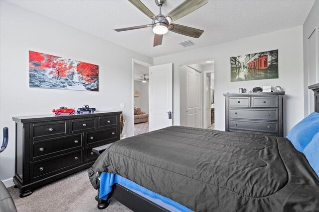 bedroom featuring light carpet, a textured ceiling, and ceiling fan