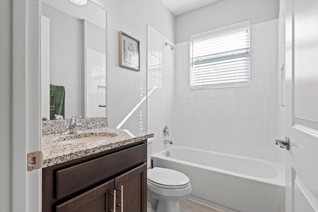 full bathroom featuring vanity, tiled shower / bath combo, and toilet