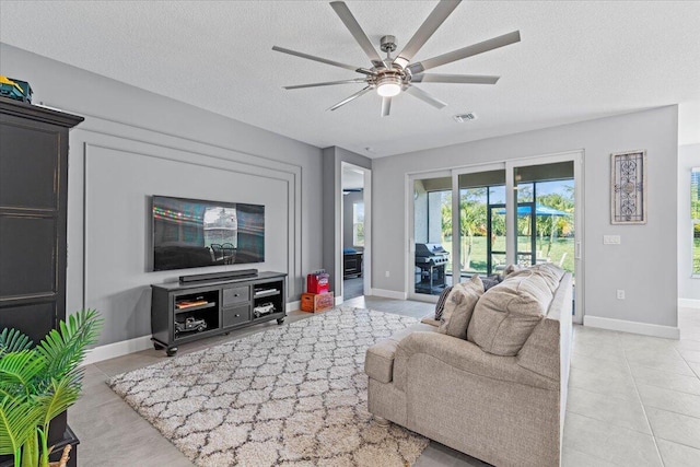 living room featuring ceiling fan, light tile patterned floors, and a textured ceiling