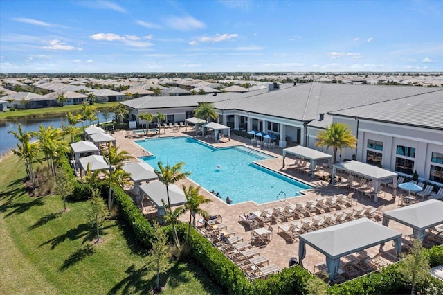 view of swimming pool with a lawn, a patio, and a water view