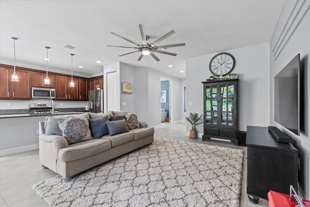 living room with ceiling fan, a textured ceiling, and light tile patterned floors