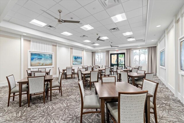 dining area with a drop ceiling, a tray ceiling, and ceiling fan