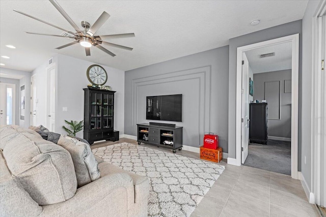 tiled living room with ceiling fan and a textured ceiling