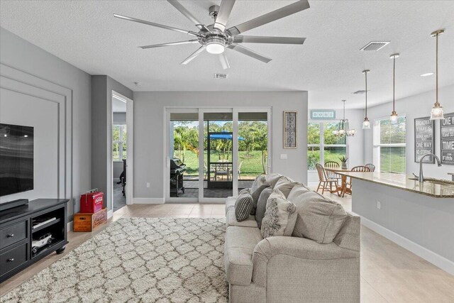 living room featuring ceiling fan, sink, and a textured ceiling