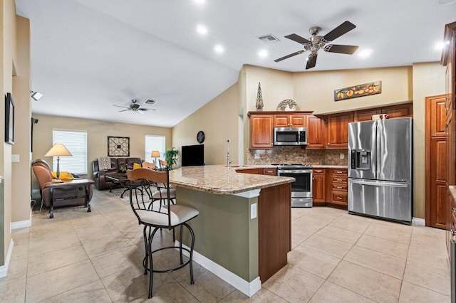 kitchen featuring light stone counters, kitchen peninsula, a kitchen breakfast bar, appliances with stainless steel finishes, and ceiling fan