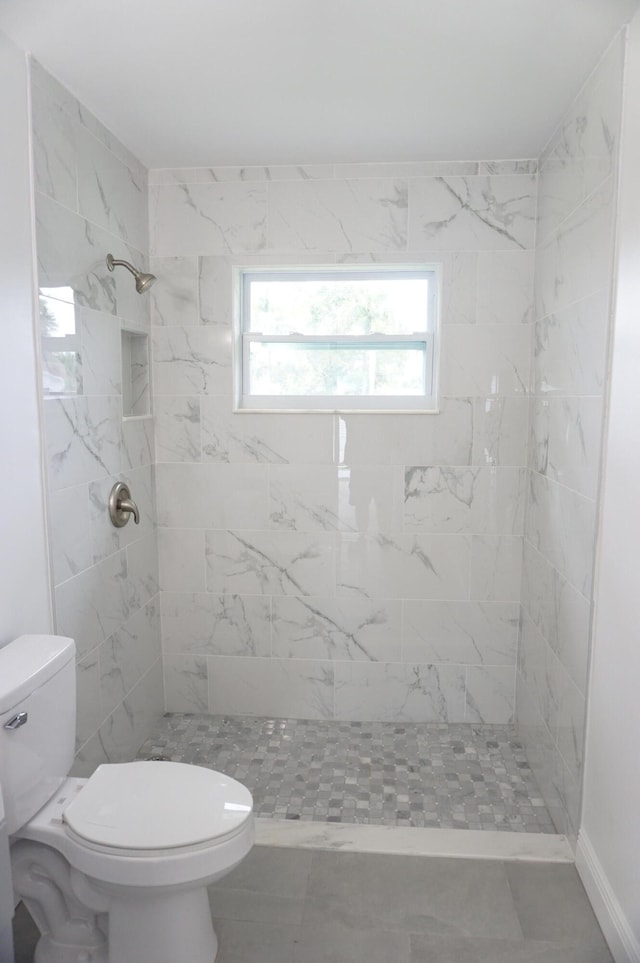 bathroom featuring a tile shower and toilet