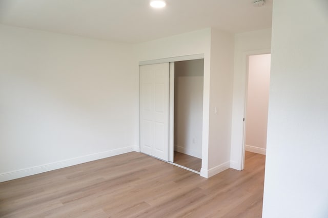 unfurnished bedroom featuring light wood-type flooring and a closet