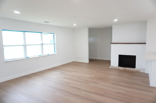 unfurnished living room with light wood-type flooring and a fireplace