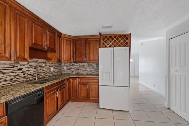 kitchen with dark stone countertops, dishwasher, light tile patterned floors, white fridge with ice dispenser, and sink