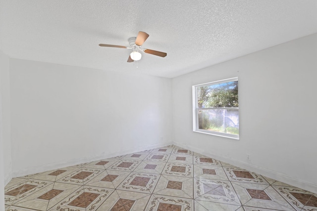 spare room featuring ceiling fan, light tile patterned flooring, and a textured ceiling