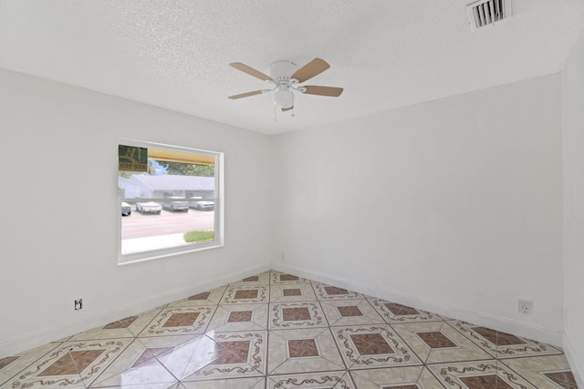 tiled spare room with a textured ceiling and ceiling fan