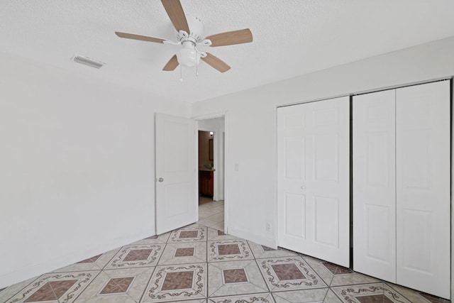 unfurnished bedroom featuring a textured ceiling, light tile patterned floors, ceiling fan, and a closet