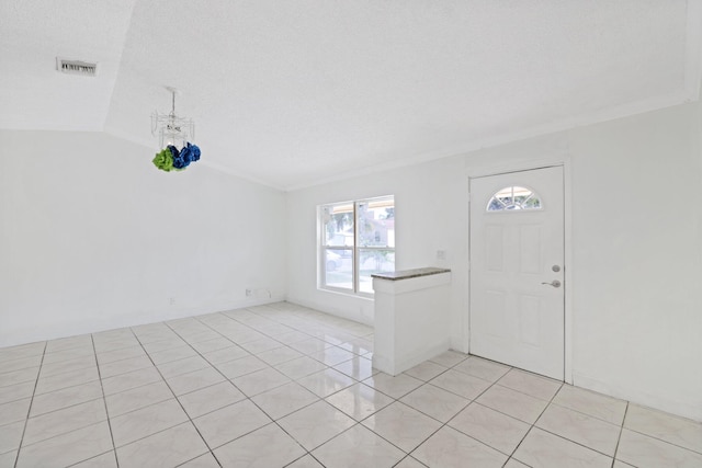 tiled entryway featuring ornamental molding, a textured ceiling, and vaulted ceiling