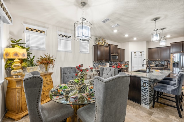 dining space with an inviting chandelier, a textured ceiling, and sink