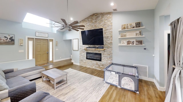 living room with ceiling fan, a fireplace, wood-type flooring, and high vaulted ceiling