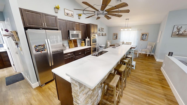 kitchen featuring hanging light fixtures, stainless steel appliances, lofted ceiling, ceiling fan, and light hardwood / wood-style flooring