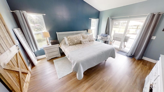 bedroom with access to outside, lofted ceiling, and light hardwood / wood-style floors